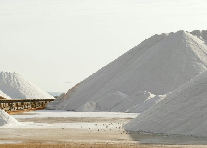 Expansive view of salt mountains and conveyor belt in a salt mine, showcasing industrial beauty.